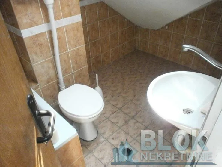 Small tiled bathroom with a toilet, washbasin, and sloping ceiling.