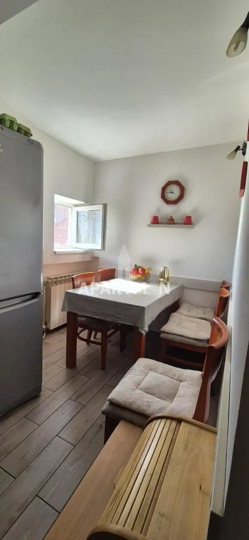 Dining area with a wooden table, chairs, and a refrigerator.