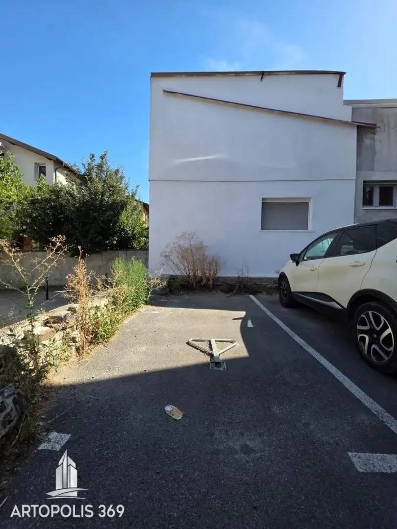 Asphalted parking space with a barrier in front of the building.