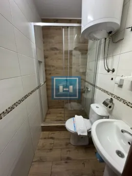 Compact bathroom with a shower cabin, sink, toilet, and water heater. - image 15