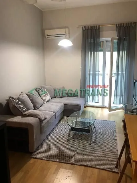 Dnevna soba sa ugaonom garniturom, stočićem i izlazom na terasu.
