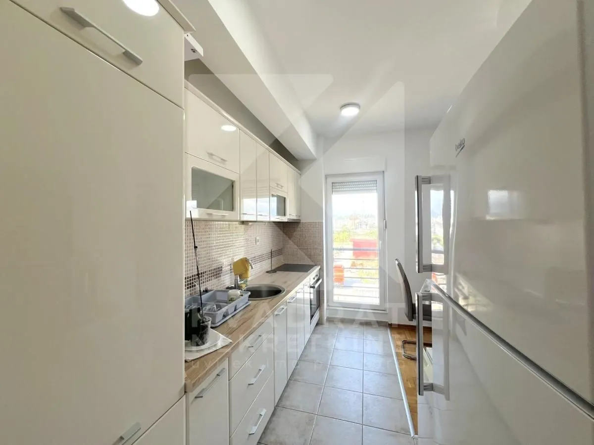 Small bright kitchen with white cabinetry and a refrigerator.