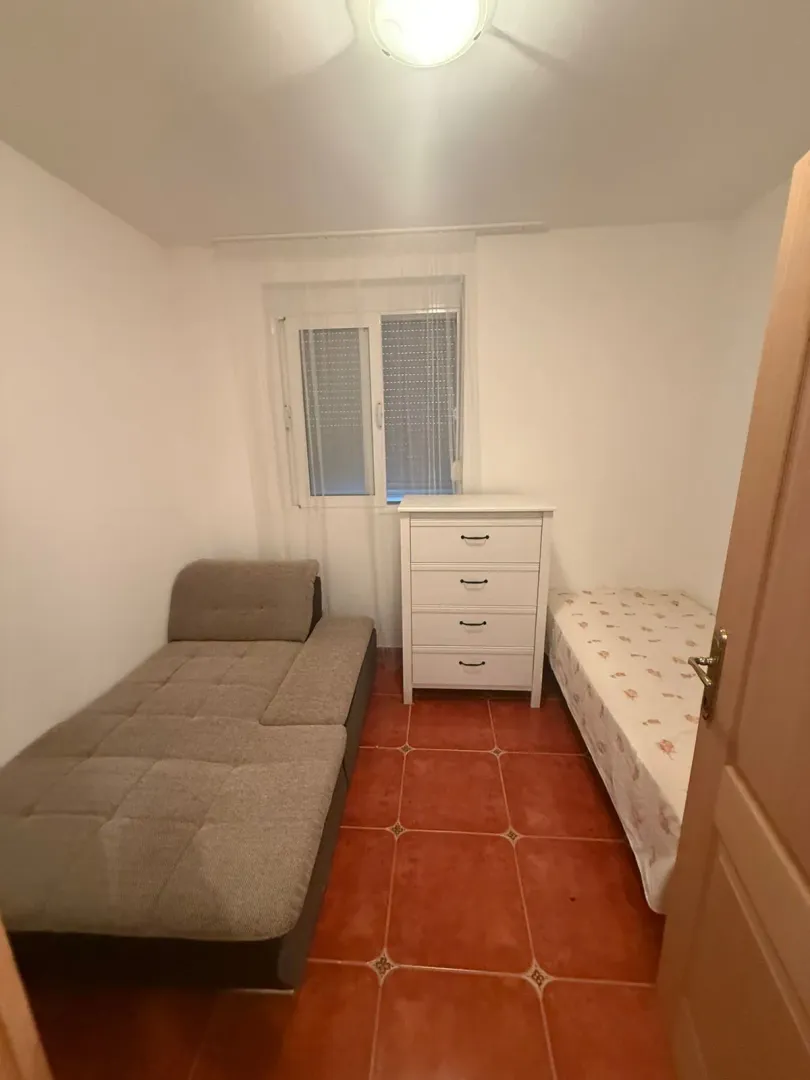 Manja spavaća soba sa dva kreveta i bijelom komodom.