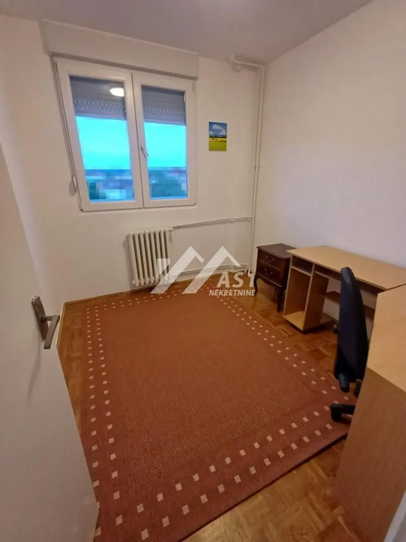 Manja soba sa radnim stolom i prozorom.