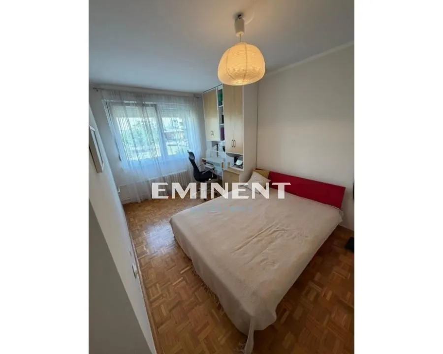 Furnished bedroom with a double bed, desk, and a window.