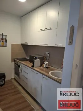 Manja bela kuhinja sa drvenom radnom pločom i ugrađenim elementima. - image 2