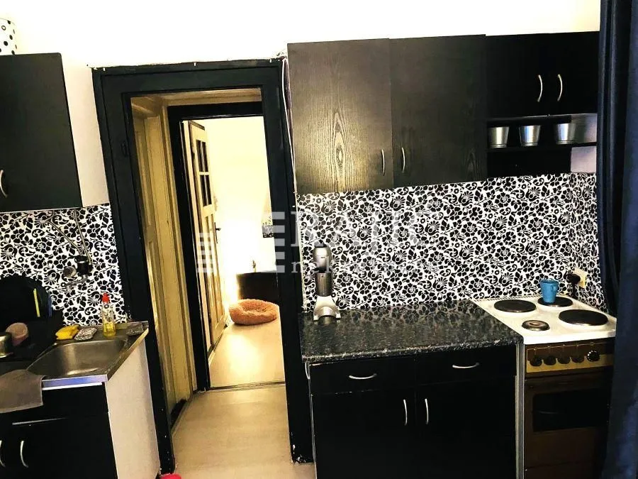 Small kitchen with black cabinets and patterned backsplash.