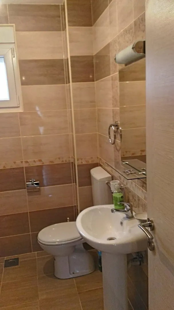 A bathroom with ceramic tiles, a pedestal sink, and a toilet.