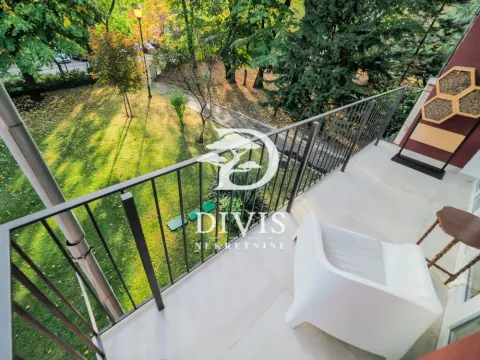 Covered balcony with an armchair and a view of greenery and the yard. - image 18