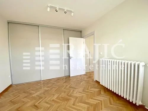 Empty room with parquet flooring, built-in wardrobe, and radiator.
