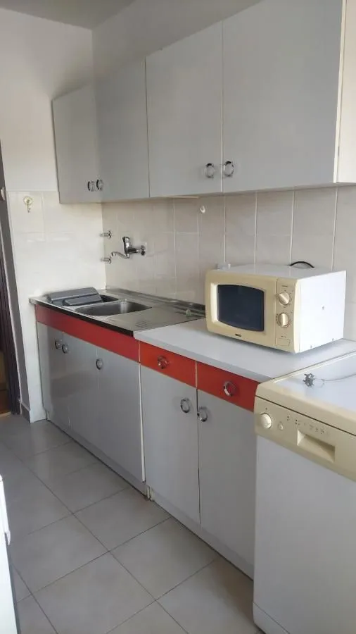 Manja kuhinja sa belim i narandžastim elementima.