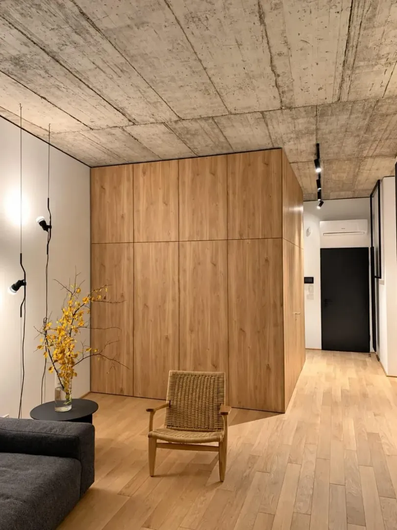 Modern interior with wooden elements, hardwood floors, and a raw concrete ceiling.