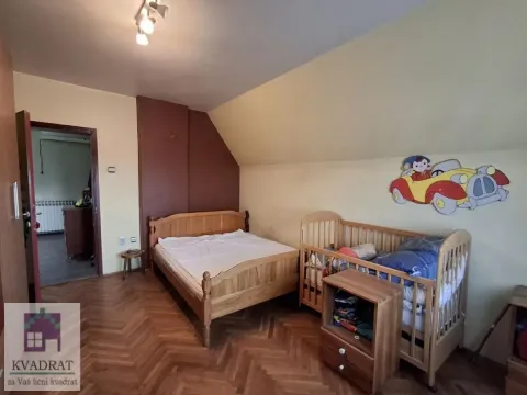 Spavaća soba sa drvenim krevetom i dečjim kreveca pod kosim krovom. - image 8