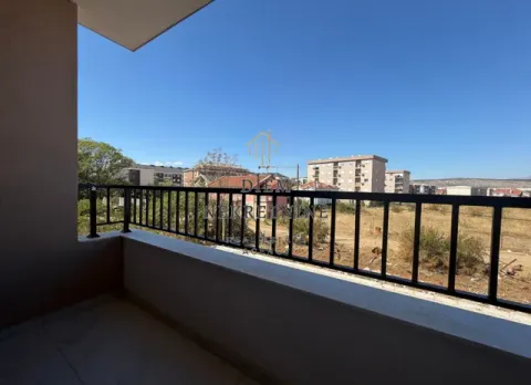 Natkriveni balkon sa crnom ogradom i pogledom na naselje. - image 3