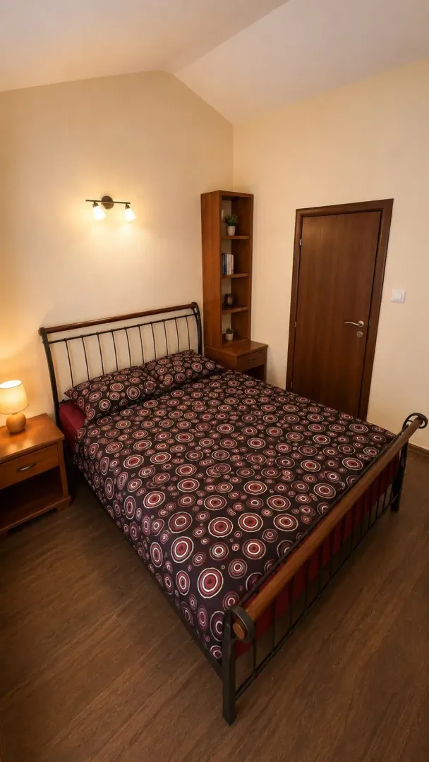 Namještena spavaća soba sa bračnim krevetom, drvenim ormarom i noćnim stočićima.