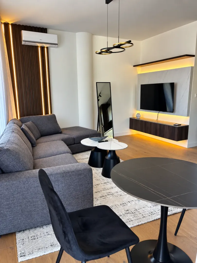 Modern living room with a sectional sofa, TV, and dining table.