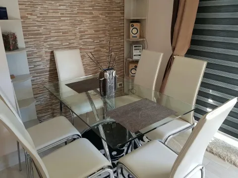 Trpezarija sa staklenim stolom i bijelim stolicama ispred ukrasnog zida. - image 6