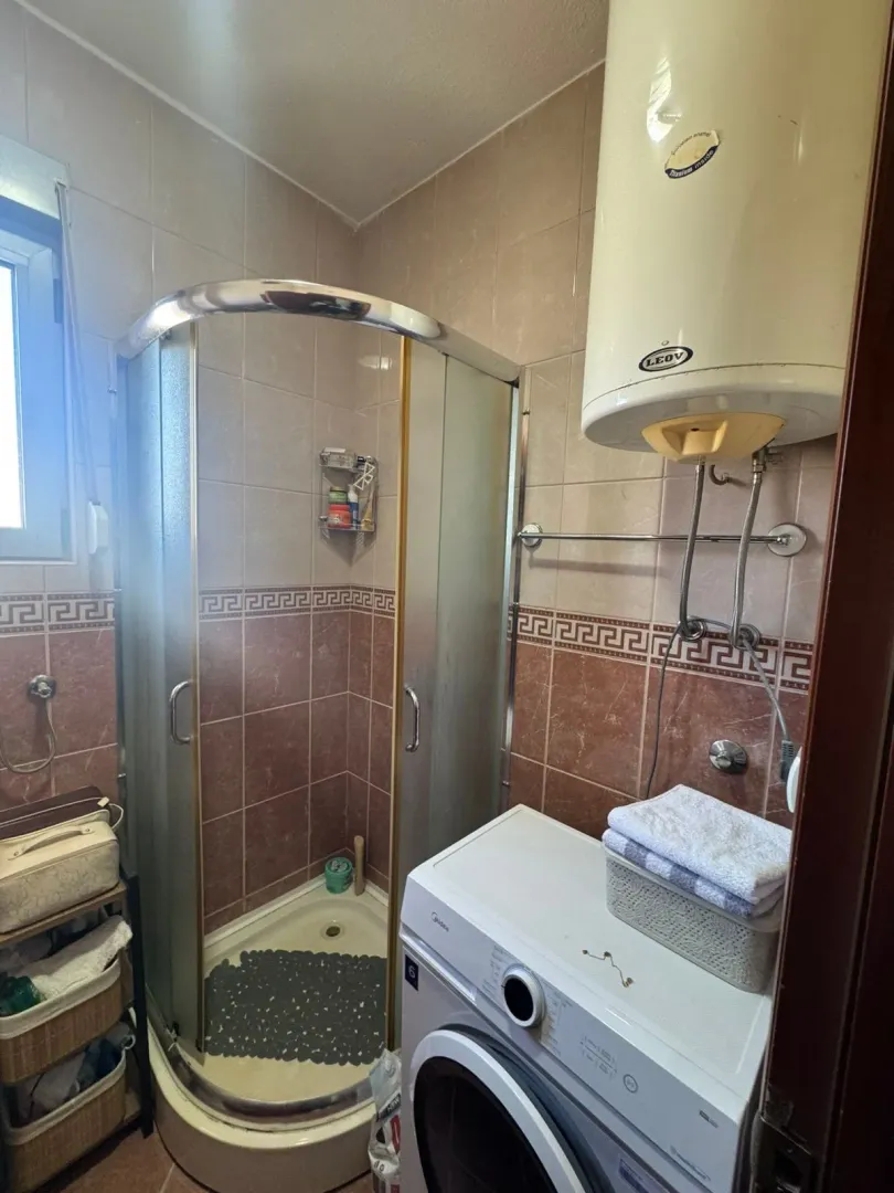 Small bathroom with a shower cabin, washing machine, and water heater.