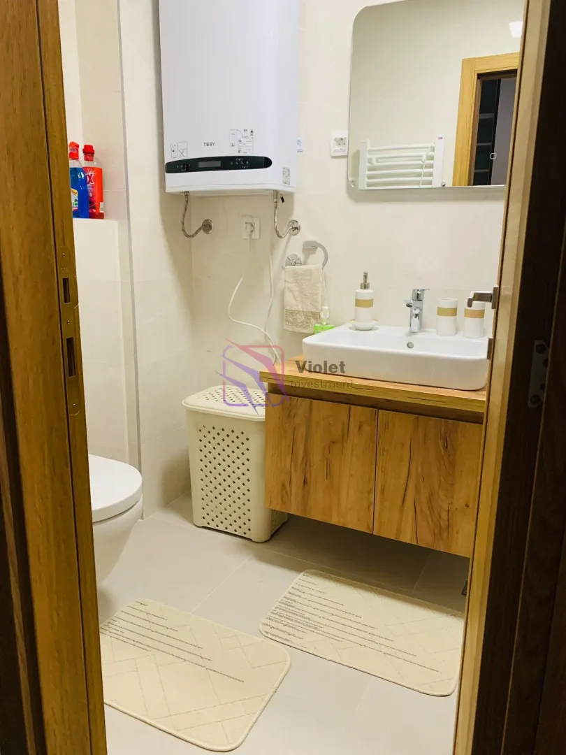 View of a modern bathroom equipped with a washbasin, toilet, and water heater.