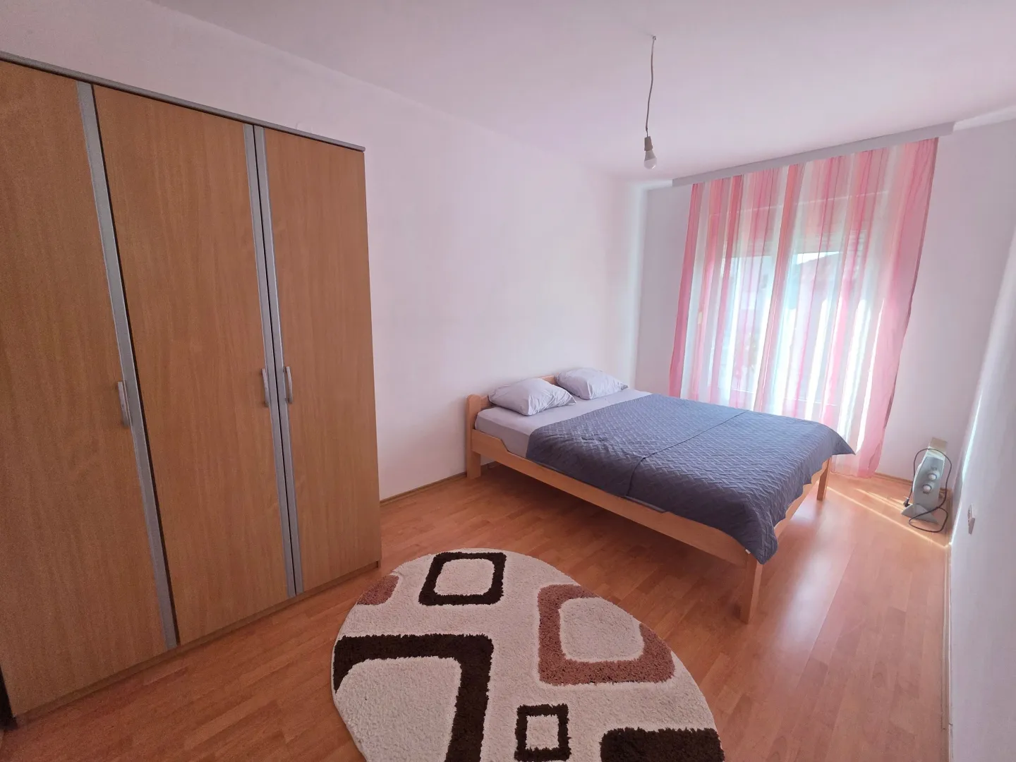Furnished bedroom with a double bed, wardrobe, and rug.