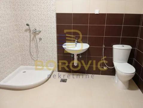 Bathroom equipped with a shower cabin, washbasin, and toilet. - image 8