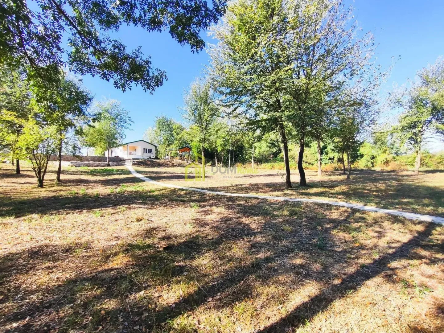 View of the spacious yard with a house and trees.