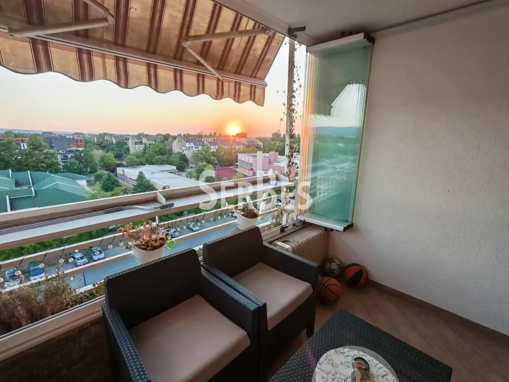 Namešten balkon sa garniturom za sedenje i pogledom na grad.