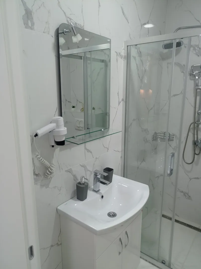 Moderne kupatilo sa umivaonikom, ogledalom i tuš kabinom.