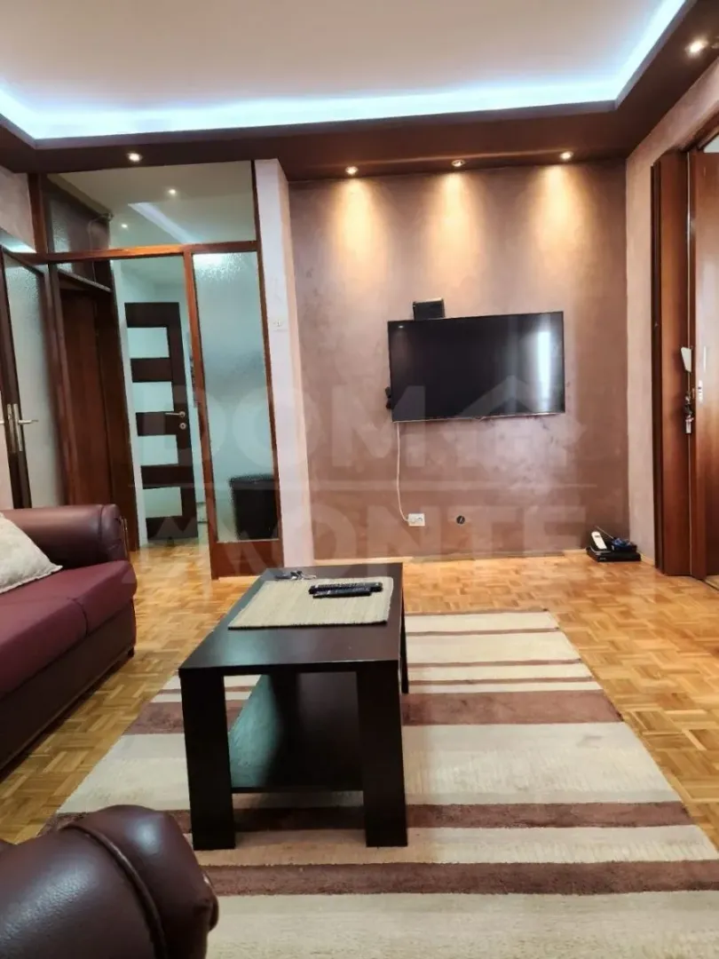 Living room with a sofa, coffee table and wall-mounted TV.