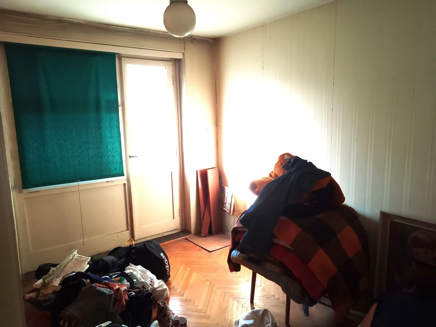 Nenamještena soba sa neredom i izlazom na terasu.
