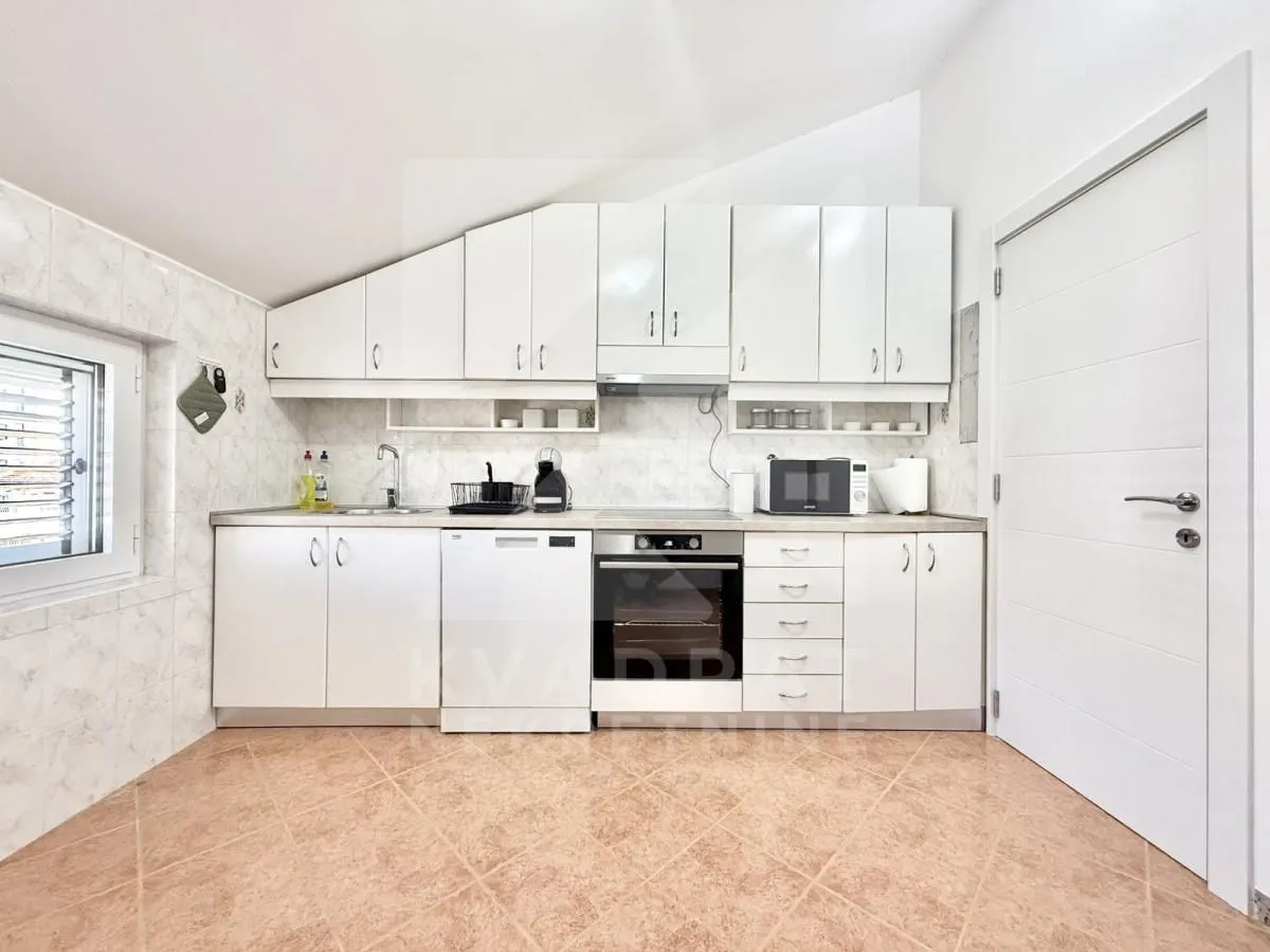 White kitchen with cabinetry and built-in appliances in the attic.