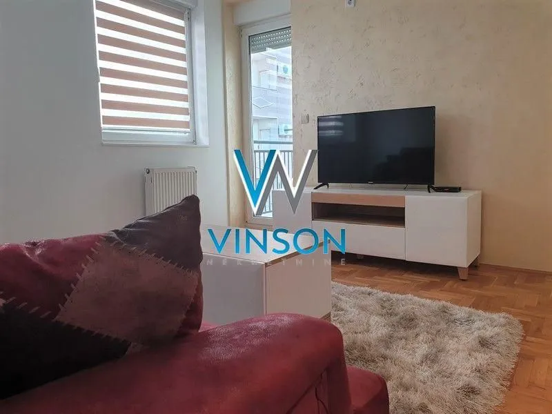 Dnevna soba sa garniturom, televizorom i izlazom na terasu.