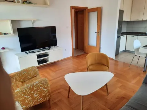 Living room with seating area, television, and a view of the kitchen in the background. - image 6