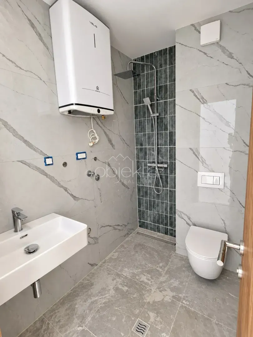 Savremeno opremljeno kupatilo sa tuš kabinom, umivaonikom i wc šoljom.