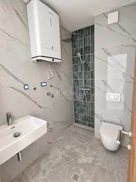 Savremeno opremljeno kupatilo sa tuš kabinom, umivaonikom i wc šoljom. - image 5