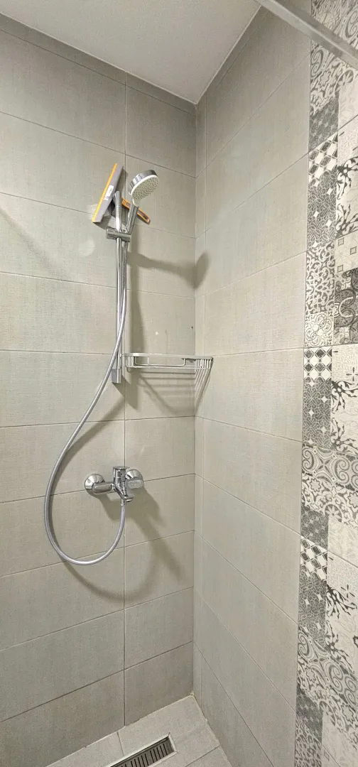 Modern shower cabin with ceramic tiles and shower mixer.