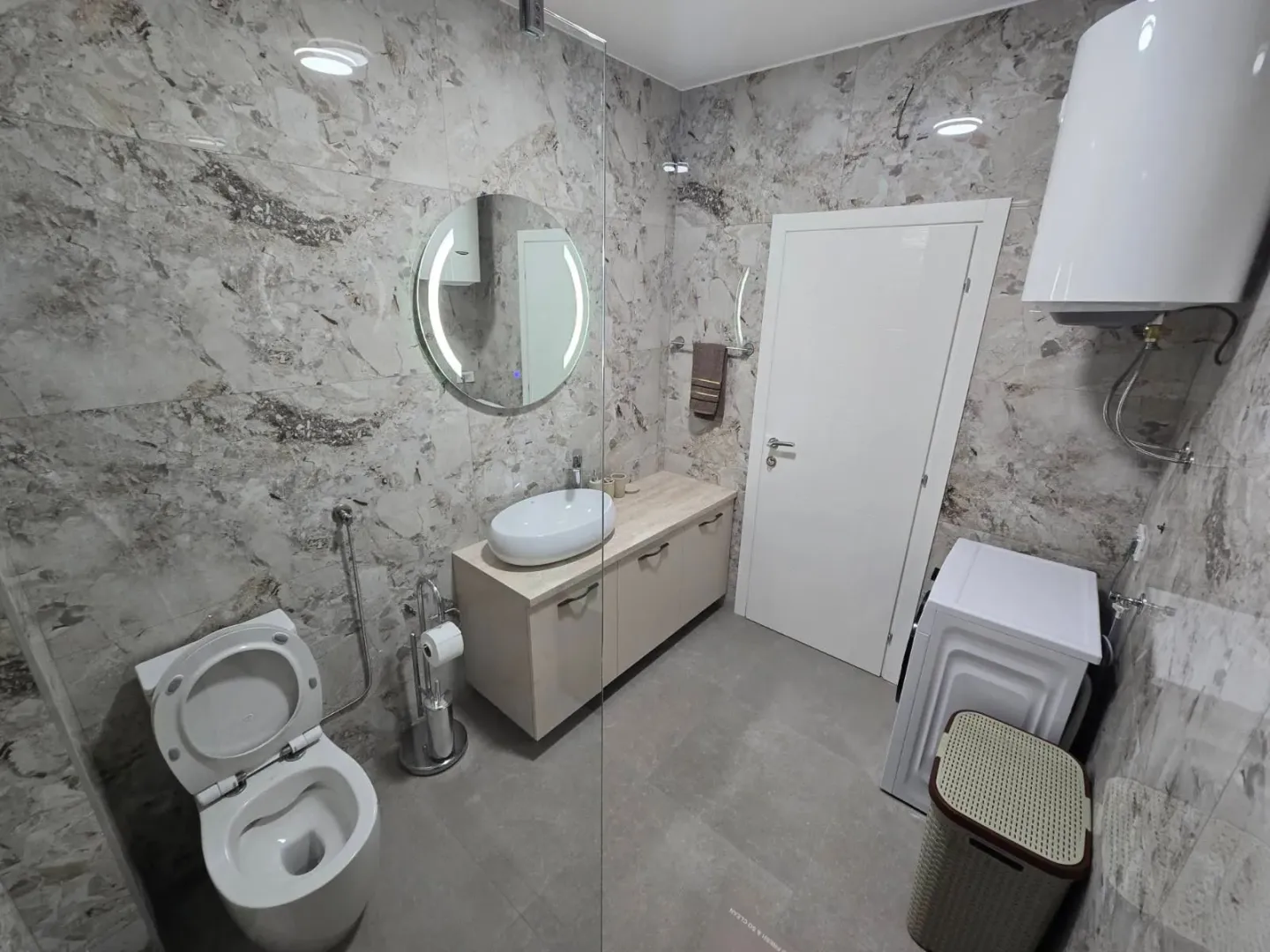 Moderne kupatilo opremljeno tuš kabinom, umivaonikom i wc šoljom.