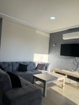 Living room with a sectional sofa, coffee table, and wall-mounted TV. - image 4