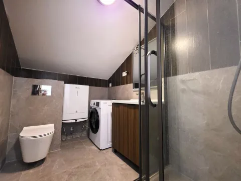 Savremeno opremljeno kupatilo sa tuš kabinom, wc šoljom, umivaonikom i veš mašinom. - image 6