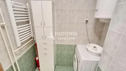 Small bathroom with a washing machine, storage cabinet, and towel warmer radiator. - image 2