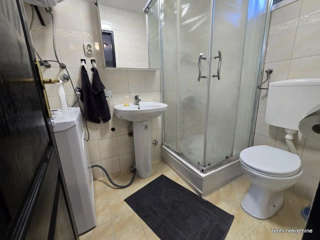 Kupatilo opremljeno tuš kabinom, umivaonikom i wc šoljom.