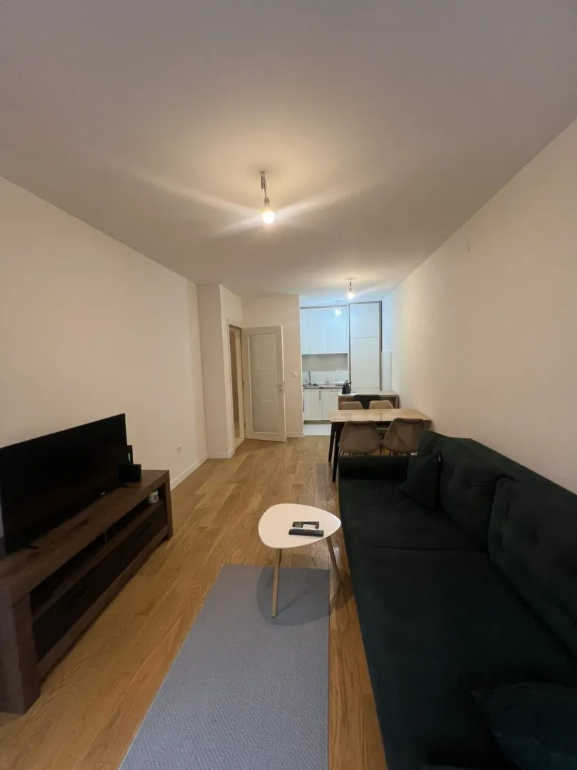 Living room with a dark sofa, television, and dining table in the background.