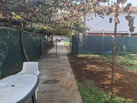 A backyard with a paved pathway, greenery, and an outdoor table. - image 2
