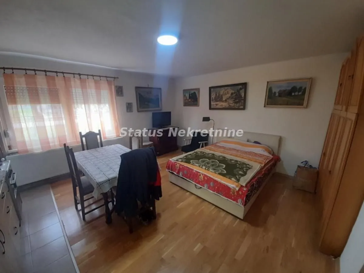 Nameštena spavaća soba sa krevetom, garderoberom i trpezarijskim stolom.