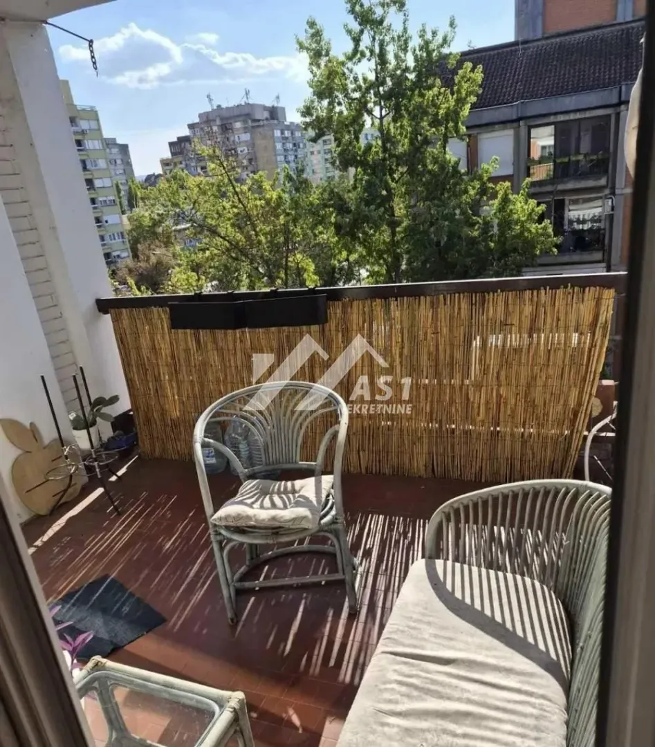 Manji namešteni balkon sa garniturom za sedenje i pogledom na grad.