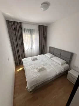 Svjetla spavaća soba sa bračnim krevetom, bijelom posteljinom i prozorom sa zavjesama. - image 3