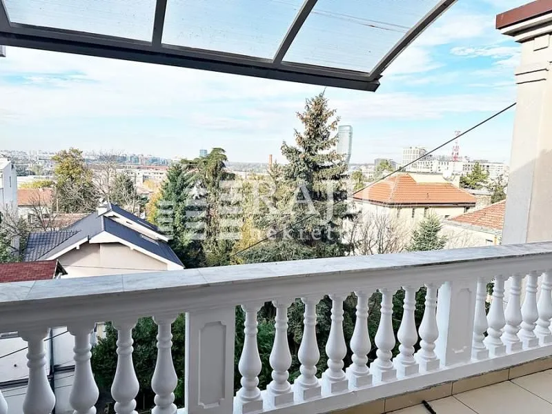 View of the city neighborhood from a spacious balcony with a white balustrade.