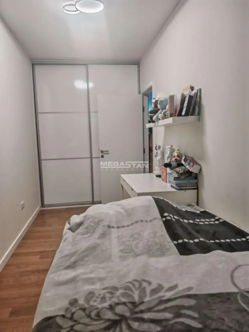 Manja spavaća soba sa krevetom, plakarom i radnim stolom.