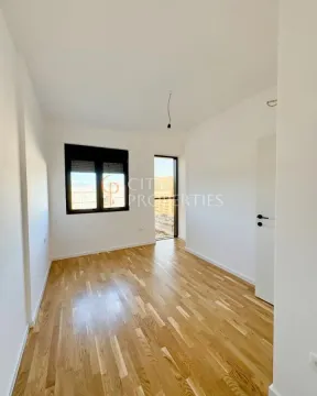Empty unfurnished room with wooden flooring, a window, and a door leading to the terrace. - image 6