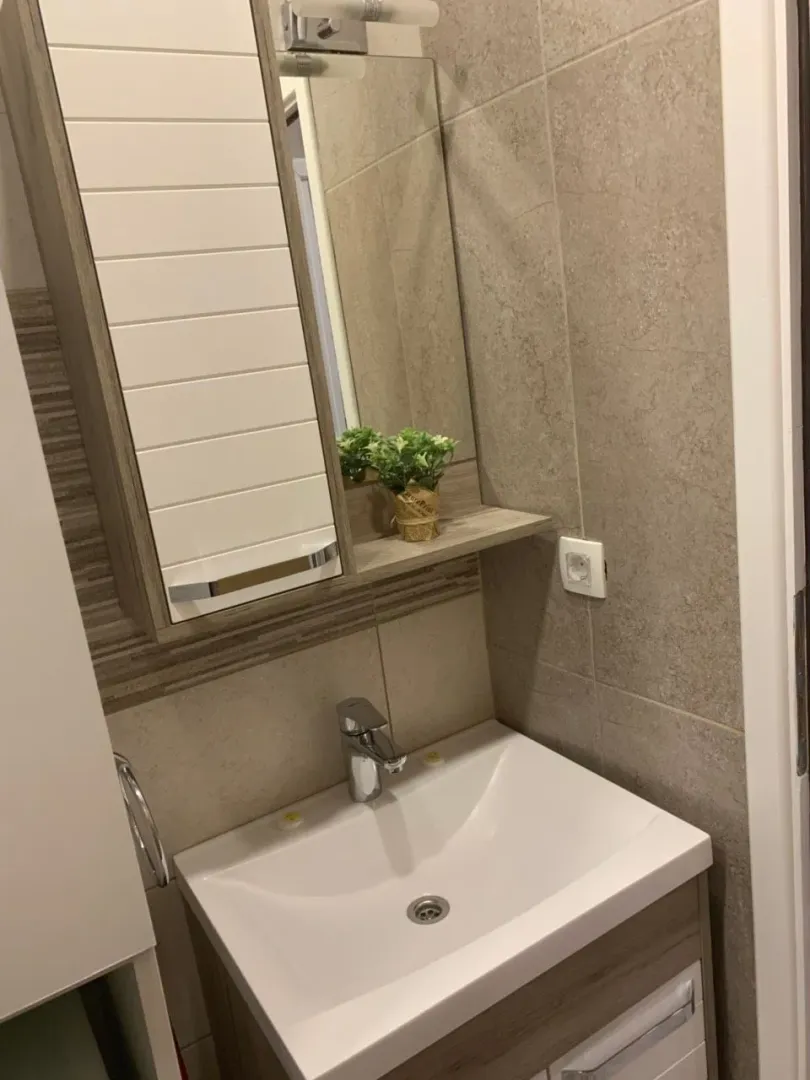 Smaller bathroom with a sink, mirror, and wall tiles.